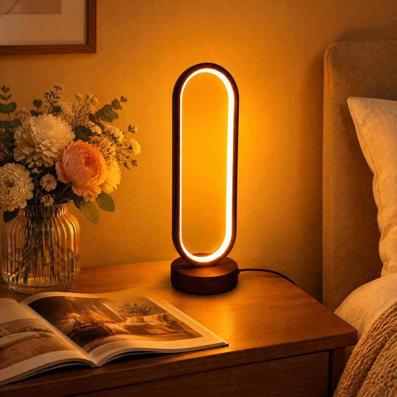 Lampe veilleuse ovale à LED allumée sur une table de chevet près d'un bouquet