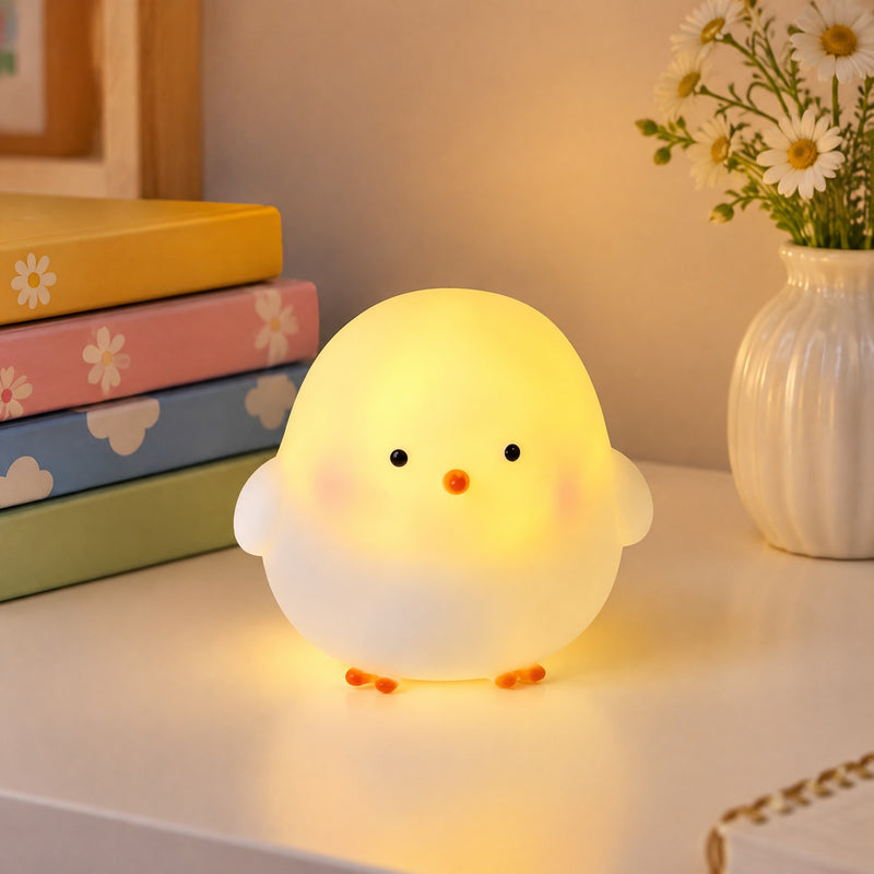 Veilleuse poussin lumineuse sur un bureau à côté de livres