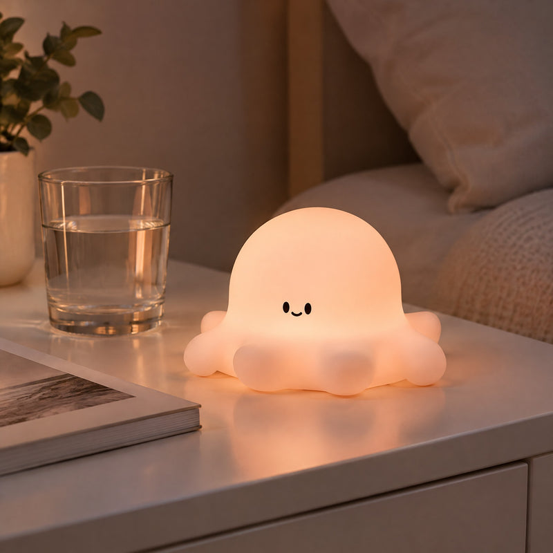 Veilleuse Pieuvre en silicone allumée sur une table de chevet, lueur rose pêche