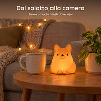 Luce notturna volpe arancione accesa su un tavolino del salotto, accanto a una tazza, senza cavo